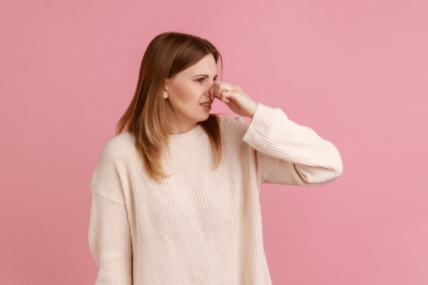 woman covering her nose due to unusual smell coming from furnace