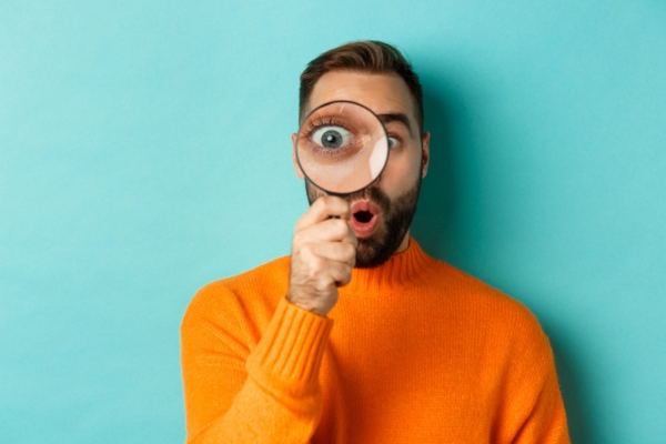 man looking through magnifying glass depicting recognizing signs of overworked furnace