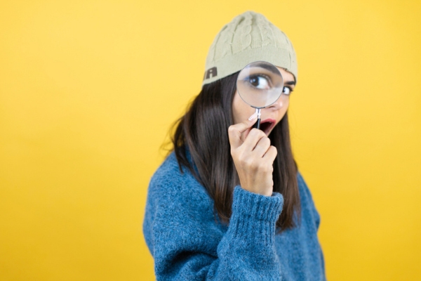 woman with magnifying glass on eye depicting identifying causes of uneven heating in house