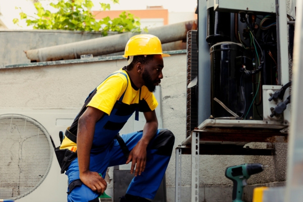 HVAC technician checking outfoor unit for debris on blades