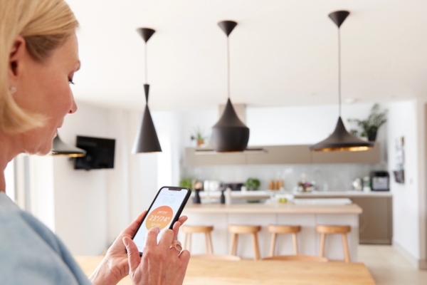 woman with programmable thermostat linked to mobile phone for energy efficiency